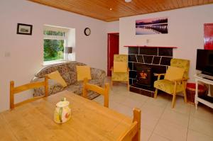 a living room with a couch and a table and a fireplace at Cottage 194 - Leenane in Leenaun
