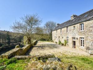 un vecchio edificio in pietra accanto a un fiume di Authentic manor house with terrace and pond a Plougonven