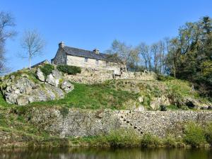 une vieille maison sur une colline à côté d'une rivière dans l'établissement Authentic manor house with terrace and pond, à Plougonven