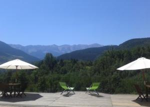 a group of chairs and umbrellas on a patio with mountains at Alberg Can Ribals in Lles