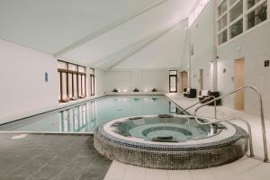 a large swimming pool with a large tub in a building at Nant Ddu Lodge Hotel & Spa by Belvilla in Merthyr Tydfil