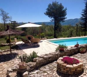 a patio with a pool and a table and an umbrella at Le bastidon du Luberon in Caseneuve