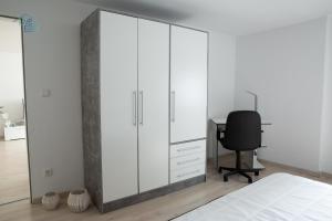 a bedroom with a large white cabinet and a desk at Bungalow near by Playmobil and fair Nuremberg in Zirndorf
