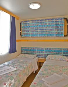 two beds in a room with a window at Arena Medulin Mobile Homes in Medulin