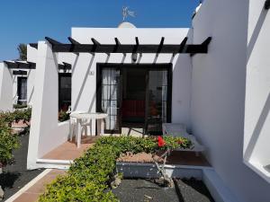 una casa blanca con pérgola y algunas plantas en Salmarina Bungalows, en Puerto del Carmen