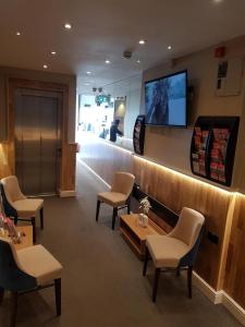 una sala de espera con sillas y TV en la pared en Ascot Hyde Park Hotel en Londres
