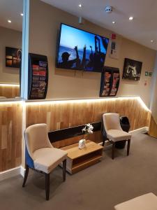 a waiting room with two chairs and a tv on the wall at Ascot Hyde Park Hotel in London +28 photos