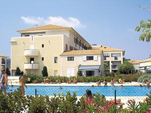 a group of people in a swimming pool in front of a building at Lagrange Vacances Le Domaine d’Azur et Tahiti Park in Le Lavandou