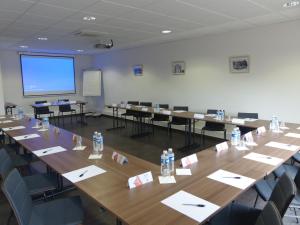 a room filled with tables, chairs, and a projector screen at ibis Périgueux Centre in Périgueux