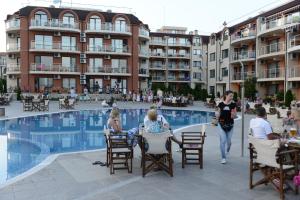 a group of people sitting at tables by a swimming pool at Sun Sea Resort in Ravda