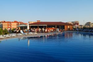 a large swimming pool with people sitting in chairs next to a building at Sun Sea Resort in Ravda