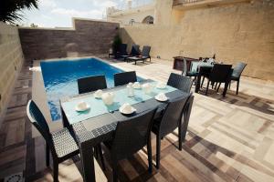 a patio with a table and chairs and a swimming pool at Soleil B&B Gozo in Għarb