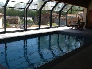 a swimming pool in a house with windows at Gîtes de la Bibudière in Le Boupère