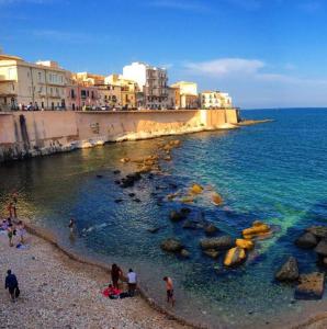 un gruppo di persone su una spiaggia vicino all'oceano di Una Terrazza per Due a Siracusa