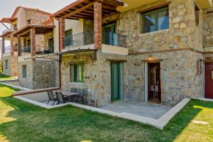 ein Steinhaus mit einer Terrasse und einem Tisch in der Unterkunft Mediterraneo Luxury Suites Halkidiki in Vourvourou