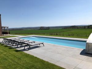 una piscina con bancos junto a un campo en Vue d'en Haut en Durbuy