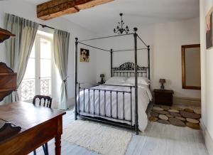 a bedroom with a metal canopy bed and a table at Appartements du Vin in Caudiès-de-Fenouillèdes