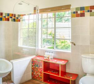 baño con lavabo y aseo y ventana en Jacana Gardens, en Harare