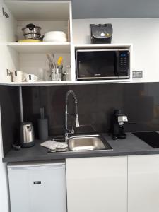 cocina con fregadero y microondas en Belvárosi apartman, en Szigetvár