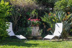 two white chairs in a garden with flowers at Villa Gabriella - Mondello in Mondello