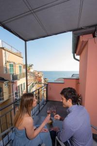 un hombre y una mujer sentados en un balcón bebiendo vino en Meb, en Riomaggiore