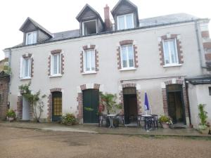 a white house with tables and chairs in front of it at Le Lurton in Château-Renault