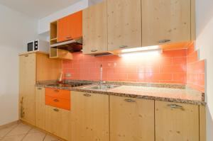 una cocina con armarios de madera y fregadero en Appartamenti Cesa Maria Mountain Hospitality, en Canazei