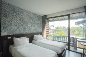 Duas camas num quarto de hotel com varanda em Anantaya Home em Phrae