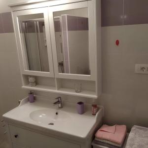 a white bathroom with a sink and a mirror at Apartments Kolorček in Izola