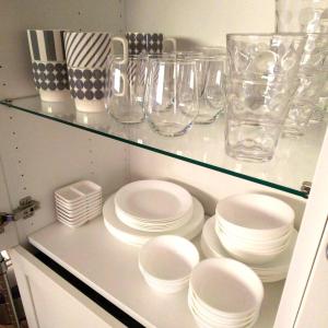 une armoire blanche avec des assiettes et des verres sur une étagère dans l'établissement villa chillon, à Shodoshima