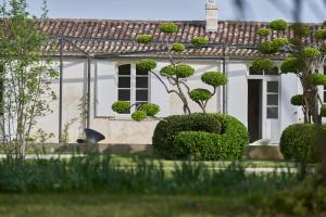 a white house with bushes in front of it at CHASSE-SPLEEN Les Chambres in Moulis-en-Médoc +18 photos