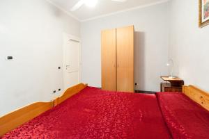 Schlafzimmer mit einem roten Bett und einem Holzschrank in der Unterkunft Mons Aureus Resort in Rom
