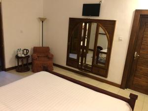 a bedroom with a bed and a mirror and a chair at Bungalow 28 in Nuwara Eliya