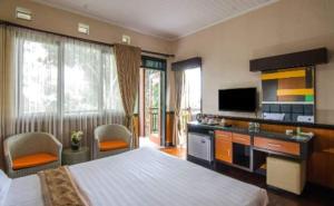 a hotel room with a bed and a television at Kebun Teh Wonosari Rollaas Hotel & Resort in Malang