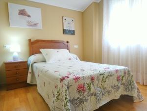 1 dormitorio con 1 cama con colcha de flores y ventana en La Casa Periquita, en Rinlo