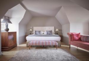 a bedroom with a bed and a red chair at Whatley Manor in Malmesbury