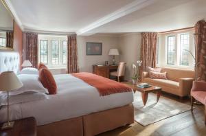a bedroom with a large bed and a living room at Whatley Manor in Malmesbury