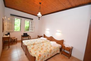 a bedroom with two beds and a table and windows at Triantafyllia's House in Agios Ioannis Pelio