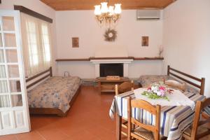 a room with two beds and a table and a fireplace at Triantafyllia's House in Agios Ioannis Pelio