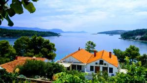 a house with an orange roof next to a lake at Apartments Vukas in Lumbarda