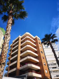 ベニドルムにあるCarlos V Apartmentのヤシの木が2本目の前にそびえる高い建物