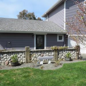 
a house with a stone wall and a wooden fence at Tanbark Shores Guest Suite in Brookings

