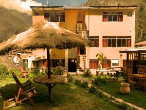 una casa con sombrilla de hierba, mesa y sillas en Inka Khawarina Tambo Lodge, en Ollantaytambo