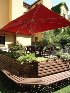 a patio with a red umbrella and tables and chairs at Hotel Marthahaus in Halle an der Saale