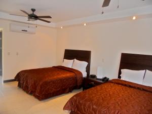 Habitación de hotel con 2 camas y ventilador de techo. en Hotel Las Espuelas, Bar & Restaurant en Liberia