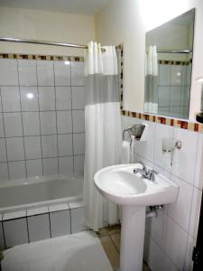 La salle de bains blanche est pourvue d'un lavabo et d'une baignoire. dans l'établissement Hotel Las Espuelas, Bar & Restaurant, à Liberia