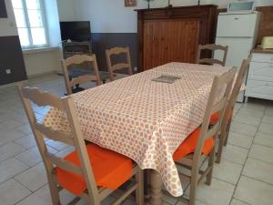 een keuken met een tafel en stoelen met een tafelkleed bij Les Hortensias in La Poultière