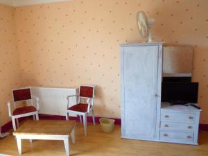 a room with a tv and a cabinet and chairs at Chez Monique in Doulaincourt