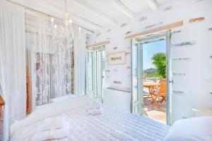 a white bedroom with a bed and a balcony at MEGAS GIALOS HARMONY in Megas Yialos-Nites