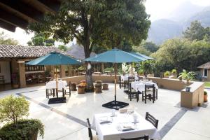 ein Restaurant mit weißen Tischen und blauen Sonnenschirmen in der Unterkunft Hotel Boutique Casa de Campo Malinalco in Malinalco
